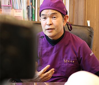 보라 수술모·수술복 차림으로 말하는 의사(책장 앞)